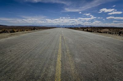 Empty road against cloudy blue sky