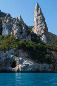 Rock formations by sea against clear sky