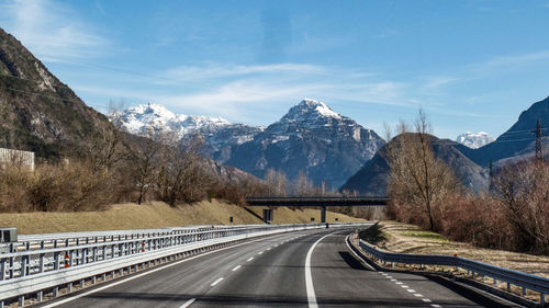 Road amidst snowcapped mountains against sky during winter