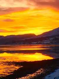 Scenic view of silhouette mountains against orange sky