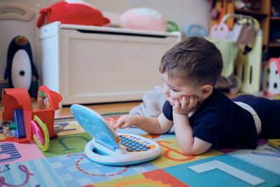 Curious little toddler playing with his toy computer