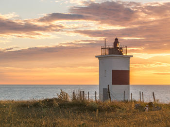 Lighthouse on beach during sunset