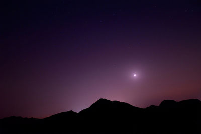 Scenic view of silhouette mountains against clear sky at night