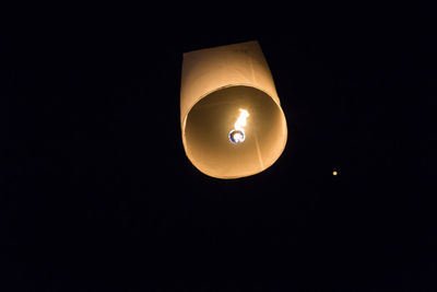 Low angle view of illuminated lamp against black background