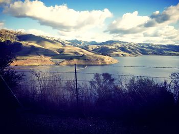 Scenic view of lake by mountains against sky