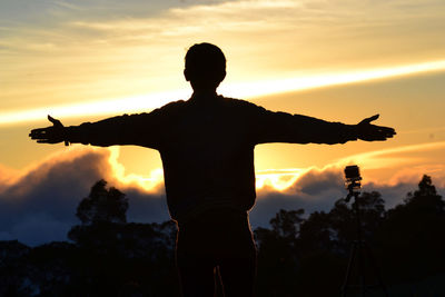 Rear view of silhouette man standing against sky during sunset