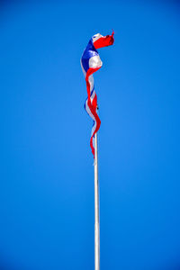 Low angle view of flag against clear blue sky