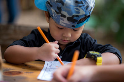 Midsection of boy holding pencils