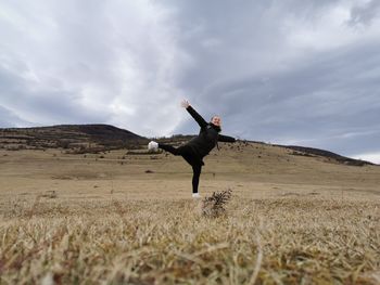 Stay positive, girl with arms raised on field against sky