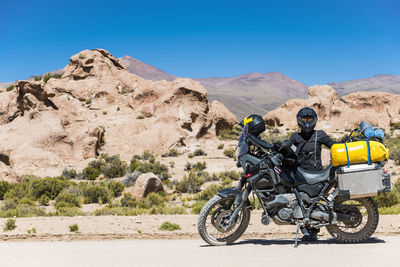 Woman standing next to touring motorcycle on dusty road in bolivia