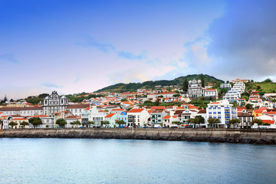 Houses by sea against sky in town