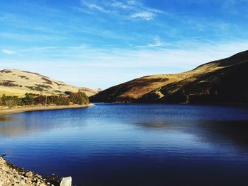 Scenic view of lake and mountains against blue sky