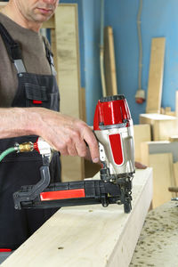 Stapling of wooden parts with a red pneumatic stapler. furniture manufacture. vertical orientation.