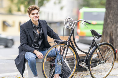 Portrait of young man sitting on bicycle in city