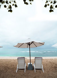 Still life shot of two deck chairs under an umbrella on beach