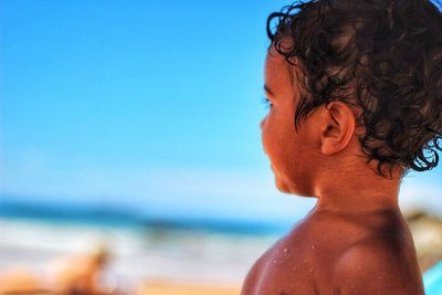 Close-up of shirtless boy at beach against sky