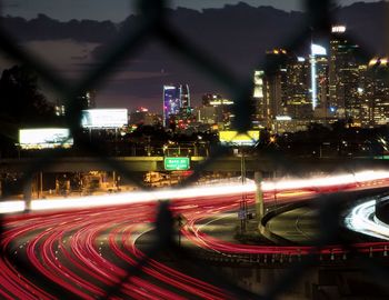 Light trails on road amidst buildings in city at night