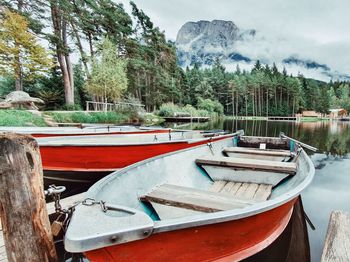 Boats moored by lake against sky