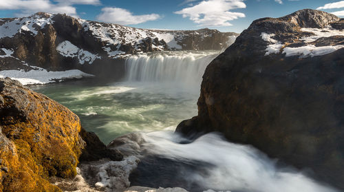 Scenic view of waterfall in mountains at winter