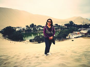 Portrait of woman in sunglasses standing on desert at oasis