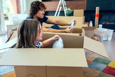 Father and son with plates sitting in cardboard boxes at home