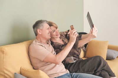 Young woman using mobile phone while sitting on bed at home