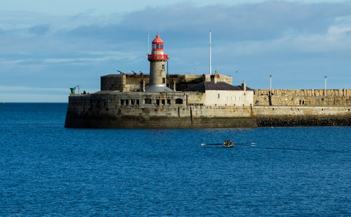 Lighthouse by sea against sky