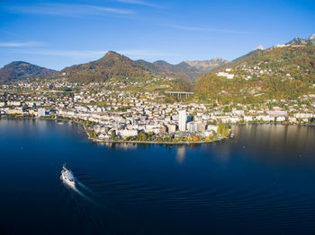 Aerial view of townscape by sea against blue sky