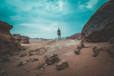 Man standing on rock against sky