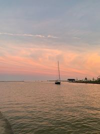 Sailboat in sea against sky during sunset
