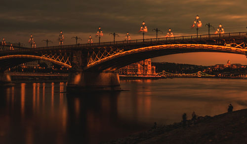 Arch bridge over river during sunset
