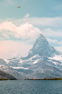 Scenic view of lake by snowcapped mountains against sky