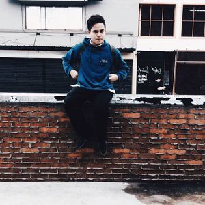 Full length of young man standing against wall