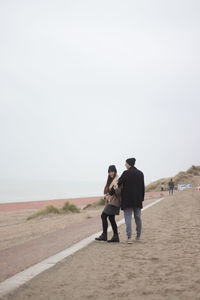 Smiling couple standing at desert against clear sky