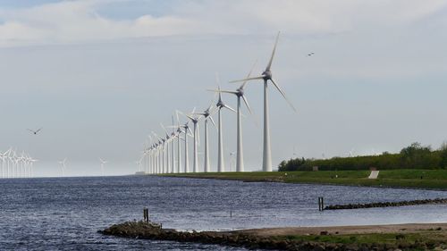 Wind turbines in water against sky