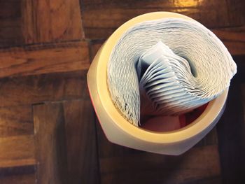 Directly above shot of tissue papers in container on wooden table