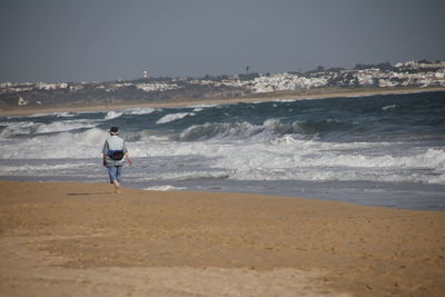 Man walking on beach against clear sky