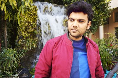 Portrait of young man standing against plants