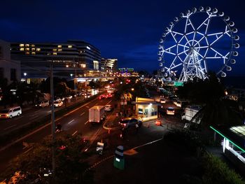 Illuminated city street against sky at night