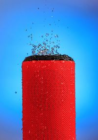 Close-up of red splashing water against blue background