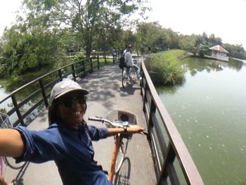 Young man riding bicycle on road by river