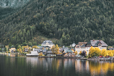 Houses by lake and buildings against mountain