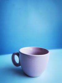 Close-up of coffee cup on table against blue background