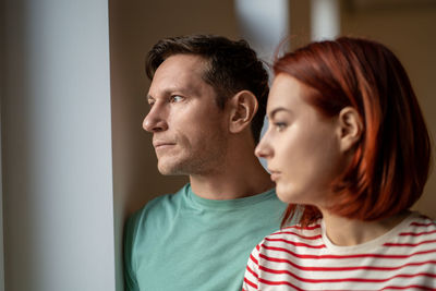 Pensive middle aged german man and woman looking out the window thinking having relationship problem