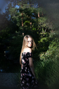 Portrait of beautiful woman standing by plants outdoors