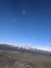 Scenic view of snowcapped mountains against blue sky