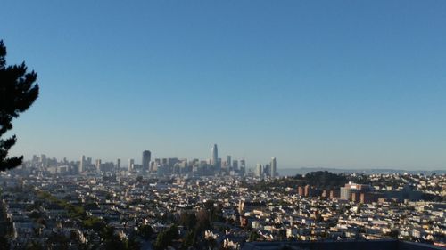 Aerial view of buildings in city against clear blue sky