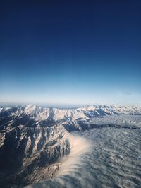 Aerial view of snowcapped mountains against clear blue sky