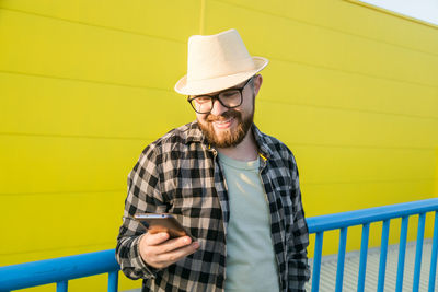 Portrait of young man standing against yellow wall