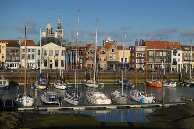 Boats moored at harbor by buildings in city